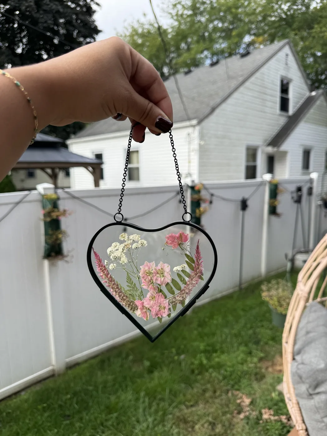 A heart-shaped hanging suncatcher of pressed pink flowers