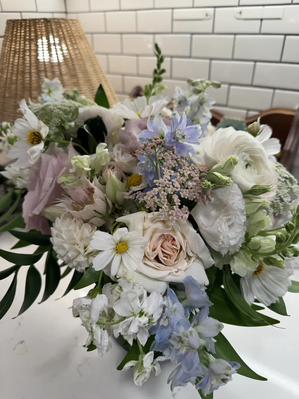 A fresh bridal bouquet of white roses, daisies, and blue delphinium