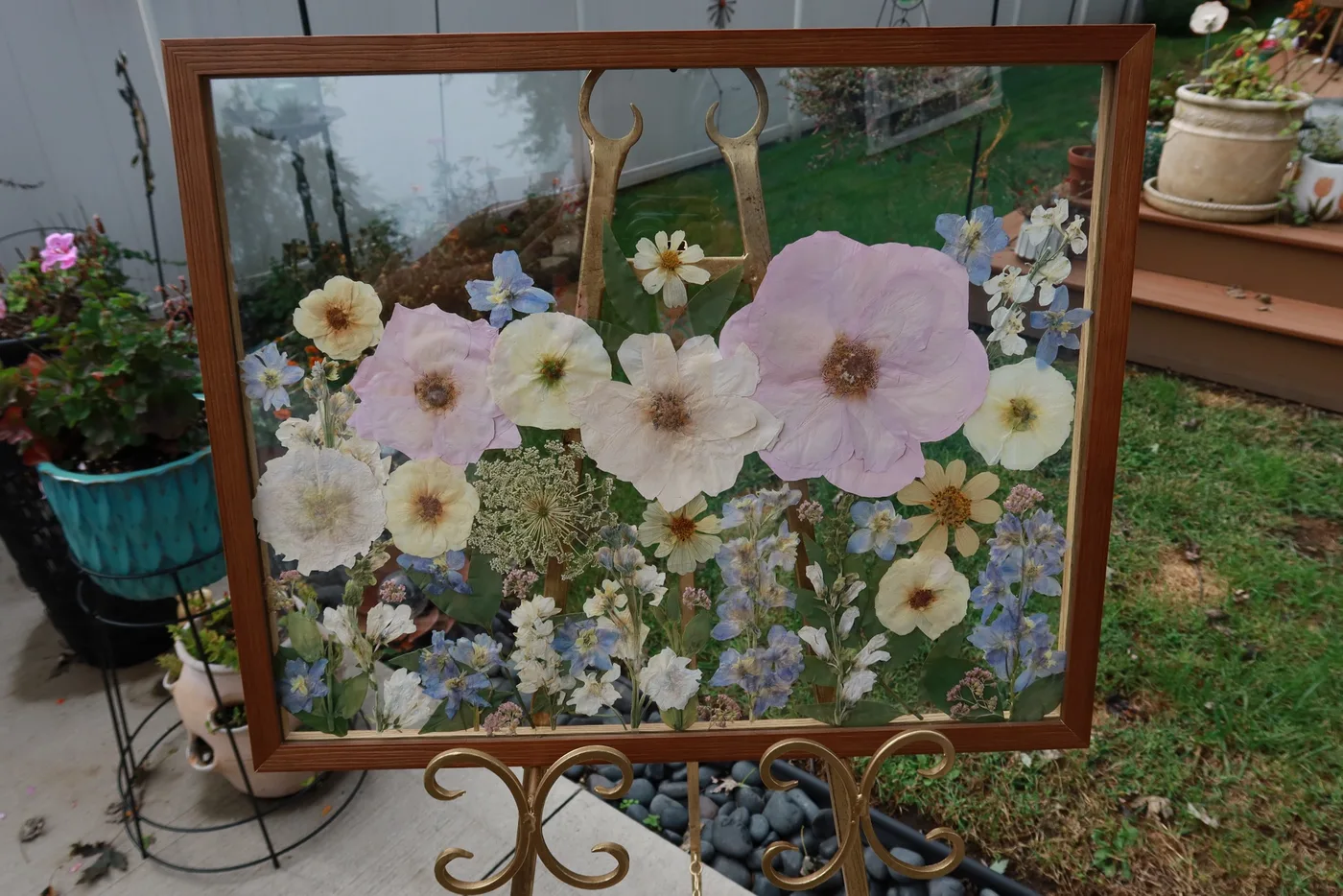 A wood-framed field of pressed pink and white flowers on an easel